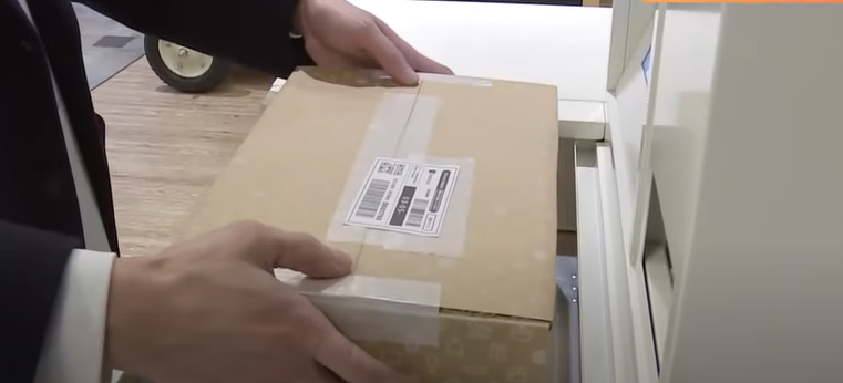 A man uses a smart machine to send a Mercari parcel.